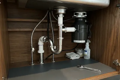 Plumber repairing a burst pipe under the sink